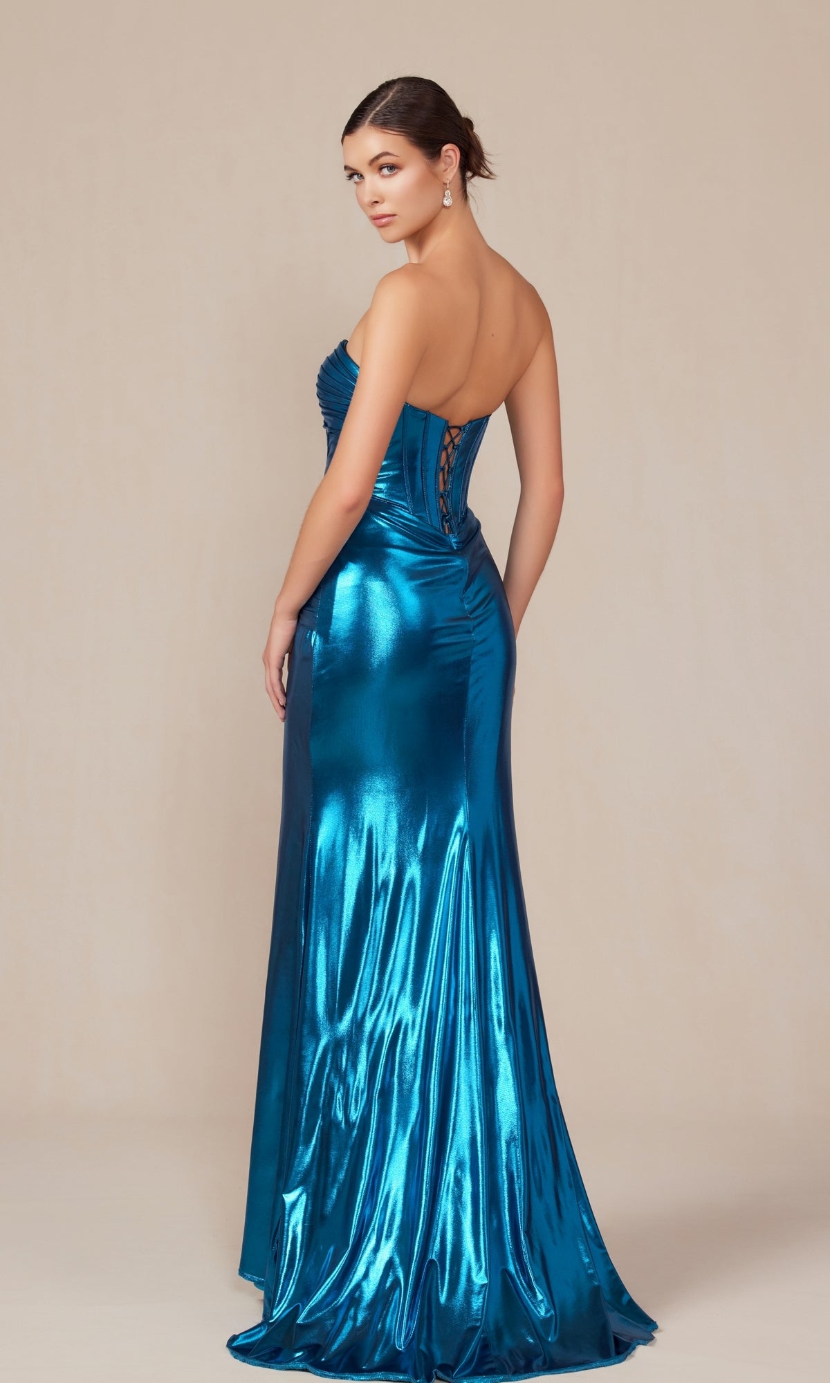 A woman wearing the Pleated Metallic Long Prom Dress: Nox Anabel T1499 in teal, featuring a strapless design and lace-up corset back, stands against a plain beige background.